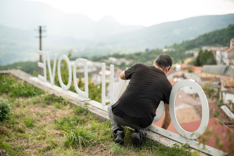 Pino Valente ripulisce l’opera Ogni dove (Latronico, 2016) dalle erbe selvatiche – photo Marco Passaro