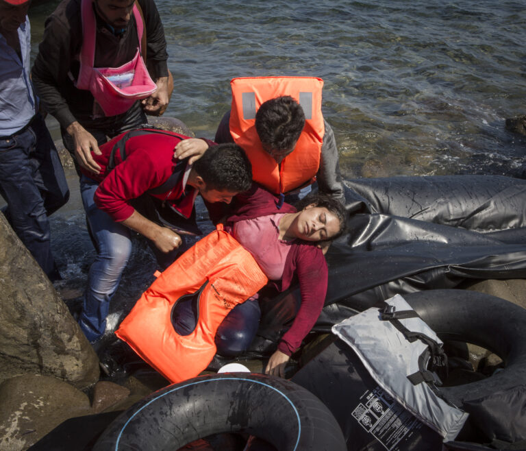 Ivor Prickett. Susan, rifugiata siriana di trentacinque anni originaria di Aleppo, sviene a causa del mal di mare e della fatica dopo aver attraversato l’Egeo dalla Turchia a Lesbo con il marito e i tre bambini. 2015, Lesbo, Grecia. Fotografia dalla serie "Seeking Shelter. Part II - West". Courtesy and © Ivor Prickett