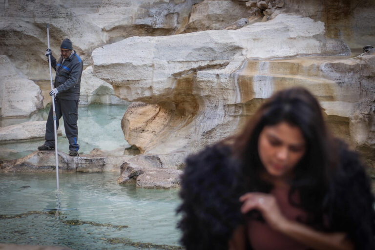 Un operaio di Acea riunisce le monete in un’unica fila mentre una turista si fa scattare una foto. Photo Alessandro Leone