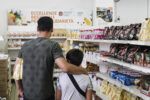 Un padre con suo figlio mentre fanno la spesa in uno degli empori Caritas. Photo Alessandro Leone