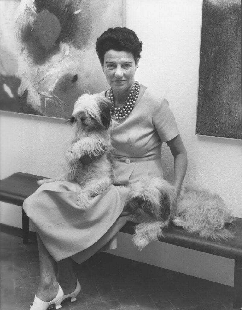 Peggy Guggenheim a Palazzo Venier dei Leoni, Venezia, anni ’50. Alle sue spalle, a sinistra, Edmondo Bacci Avvenimento #247, 1956. Photo Roloff Beny / courtesy of Archives and National Archives of Canada.