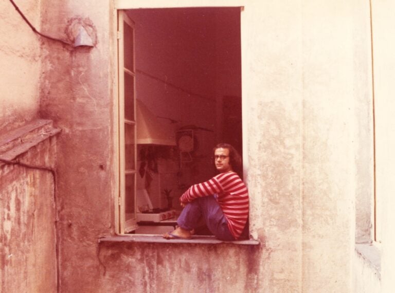 Fotografia dell’artista vestito da clown alla finestra del suo studio, Genova, 1968. Courtesy Archivio Emilio Prini